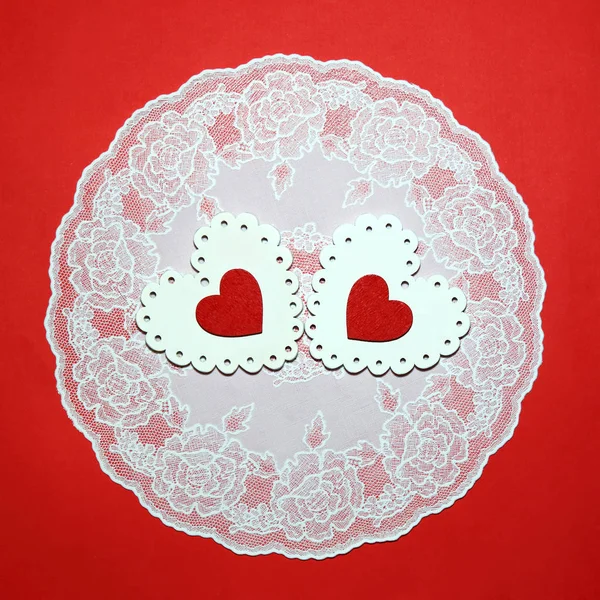 バレンタインの日、結婚式、愛。レース ナプキンお祝いや招待状の赤い背景の上に赤と白の明るい透かし彫り木製ハート. — ストック写真