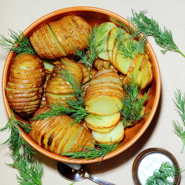 Запеченный, жареный нарезанный картофель со свежим укропом и сметаным соусом в глиняной миске . — стоковое фото