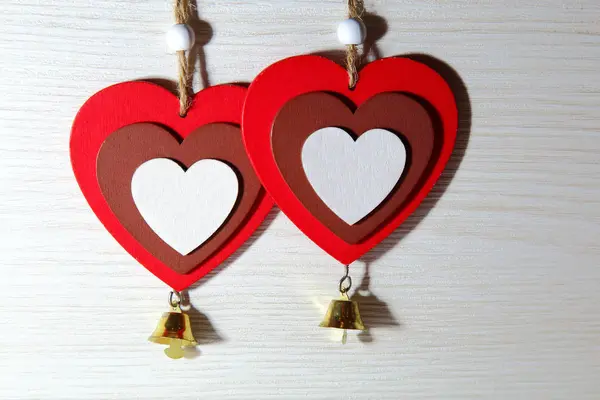 St. Valentijnsdag, liefde. Twee rode harten met klokken op een lichte houten achtergrond met een plek voor de inscriptie. — Stockfoto