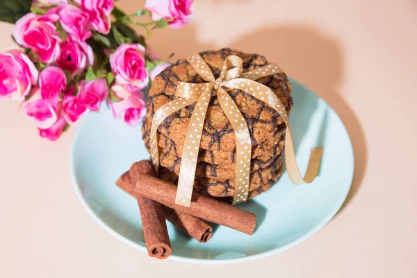 Frisch gebackene Haferflockenplätzchen auf einem blauen Teller vor Pfirsichhintergrund und ein Strauß Rosen. leckeres gesundes, süßes kulinarisches Dessert für ein romantisches festliches Frühstück, Essen — Stockfoto