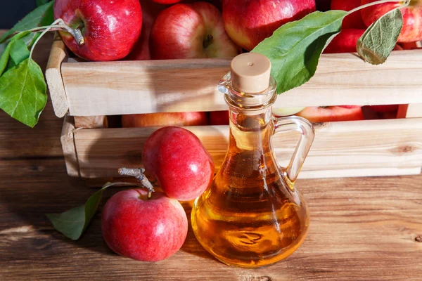 Hausgemachte Obstkonserven, gesunde Ernährung und Trinken. Apfelessig, Saft, Salatdressing aus einer Ernte reifer roter Gartenfrüchte in einem Glaskrug auf rustikalem Holzgrund — Stockfoto