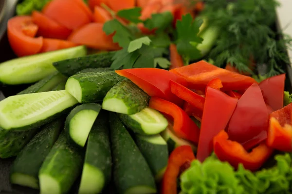 Snijd komkommers en tomaten op een bord — Stockfoto