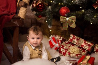 Pek çok yeteneğin bir Noel ağacı yanında oturan çocuk