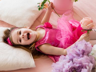 Kanepeye, yalan pembe elbiseli küçük kız müzik süre gülüyor