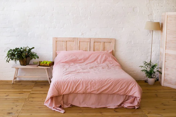 Empty bed with pink pillows and pink cover in the bedroom.
