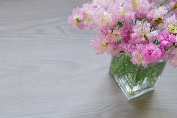 Bouquet de fleurs roses en vase sur fond bois gris — Photo
