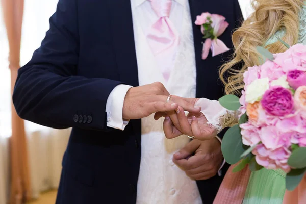 Brud sätter vigselring på brudgummar finger — Stockfoto