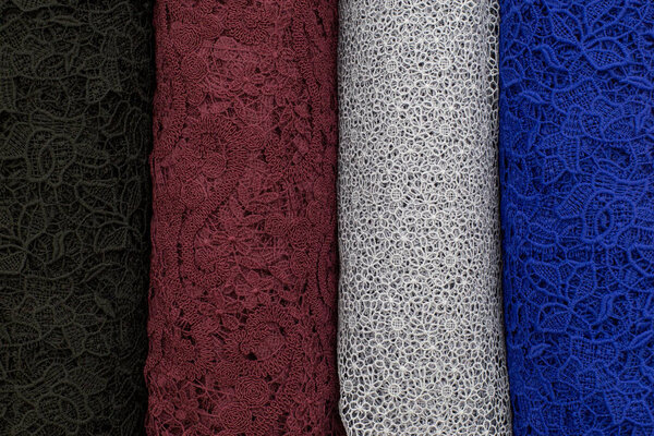 Много рулонов ткани. Болты из кружевной ткани голубого, серого, коричневого цветов
