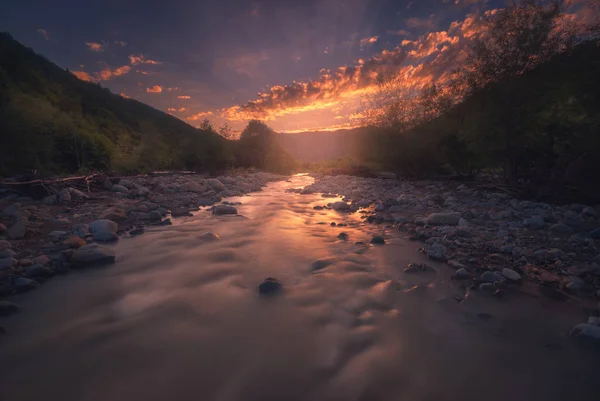 Schneller Gebirgsfluss fließt in wunderschöner Sonnenuntergangszeit — Stockfoto