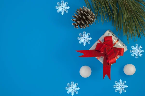 Fondo de Navidad con hermoso regalo o caja de regalo, cono de pino nevado y bolas de nieve decorativas, vacaciones. Vista superior — Foto de Stock