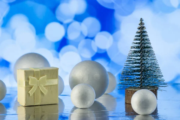 Christmas composition with Christmas tree, gift or present box and decorative snowballs against holiday lights — ストック写真