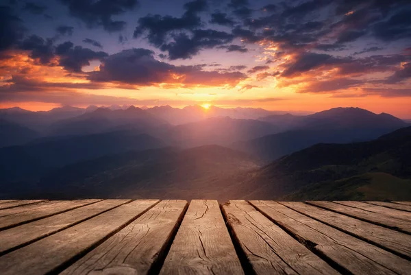Güzel bir arka plan, dağların üzerinde gün doğumu ve doğada boş ahşap bir masa. Doğal şablon manzarası