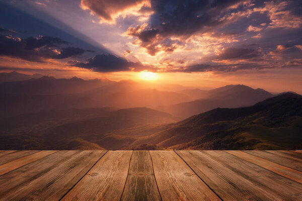 Beautiful background with sunrise over mountains and empty wooden table in nature outdoor. Natural template landscape