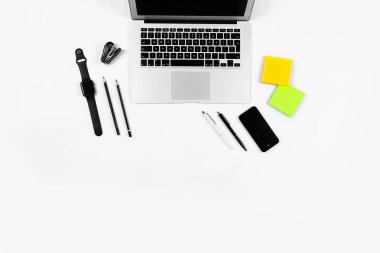 Çalışma masa üstü görünümü, düz yatıyordu. İş öğeleri beyaz bir tablo, dizüstü bilgisayar, saat, telefon, kalemler, çıkartmalar. Kopya alanı, iş öznitelikleri kavramı.