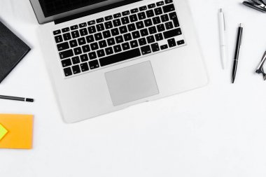 Çalışma masa üstü görünümü, düz yatıyordu. İş öğeleri beyaz bir tablo, dizüstü bilgisayar, saat, telefon, kalemler, çıkartmalar. Kopya alanı, iş öznitelikleri kavramı.