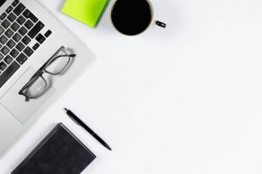 Çalışma masa üstü görünümü, düz yatıyordu. İş öğeleri beyaz bir tablo, dizüstü bilgisayar, telefon, kalemler, çıkartmalar. Kopya alanı, iş öznitelikleri kavramı.