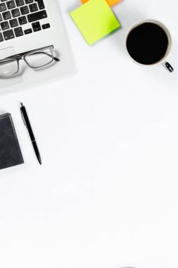 Çalışma masa üstü görünümü, düz yatıyordu. İş öğeleri beyaz bir tablo, dizüstü bilgisayar, telefon, kalemler, çıkartmalar. Kopya alanı, iş öznitelikleri kavramı.