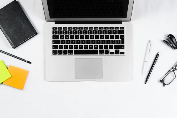 Mesa de trabajo vista superior, plano laico. Artículos de negocios en una mesa blanca, portátil, reloj, teléfono, bolígrafos, pegatinas. Espacio de copia, Concepto de atributos de negocio . —  Fotos de Stock