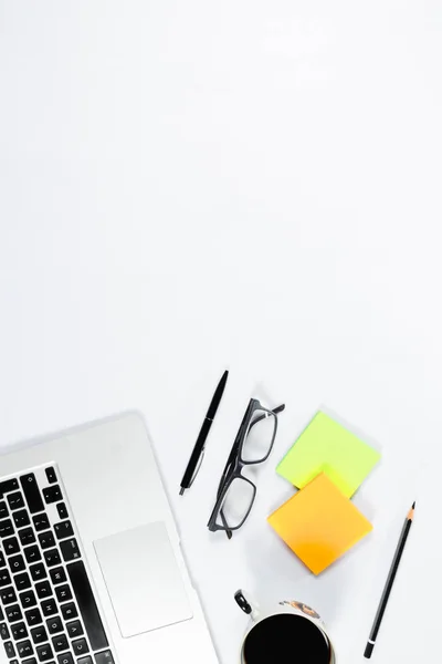 Mesa de trabajo vista superior, plano laico. Artículos de negocios en una mesa blanca, portátil, teléfono, bolígrafos, pegatinas. Espacio de copia, Concepto de atributos de negocio . — Foto de Stock