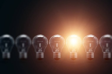 Bir dizi elektrik ampulleri, tek, karanlık bir arka planda parlıyor. Birkaç denemeden, başarılı bir konsept. Başarılı bir fikir.