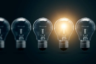 Bir dizi elektrik ampulleri, tek, karanlık bir arka planda parlıyor. Birkaç denemeden, başarılı bir konsept. Başarılı bir fikir.