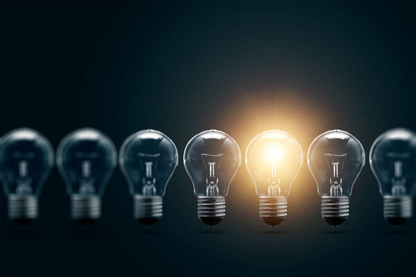 Серия электрических лампочек, только одна светится, на темном фоне. Концепция нескольких попыток, одна успешная. Успешная идея
.