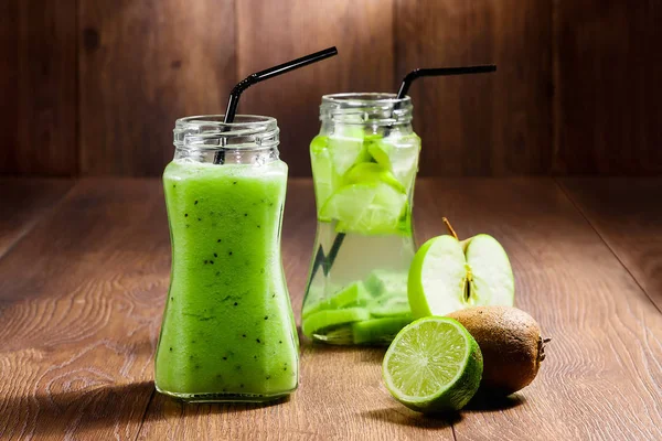 Green cocktail in a glass jar of kiwi, green apple, mint and lime on a wooden brown background. A refreshing drink. The concept of healthy eating, detox.