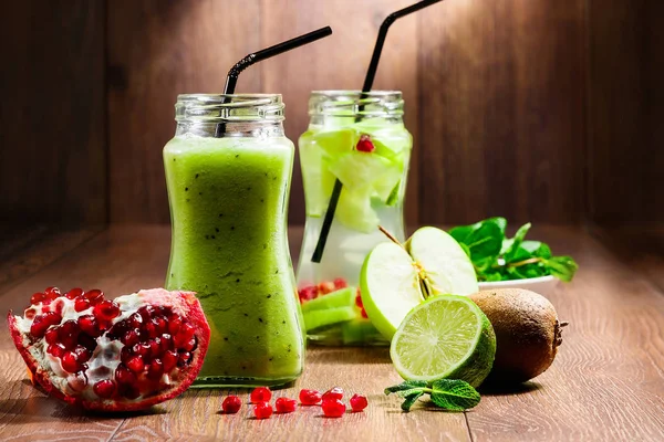Zöld koktél egy üvegedénybe, kiwi, zöld alma, menta, lime és gránátalma fa barna alapon. Egy frissítő italt. A koncepció az egészséges táplálkozás, méregtelenítés. — Stock Fotó