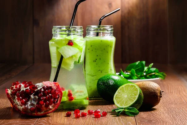 Green cocktail in a glass jar of kiwi, green apple, mint, lime and pomegranate on a wooden brown background. A refreshing drink. The concept of healthy eating, detox. — Stock Photo, Image