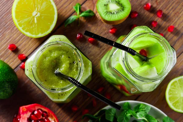 Green cocktail in a glass jar of kiwi, green apple, lime, mint and granate. The concept of a healthy diet, detox. A refreshing drink. View from above.