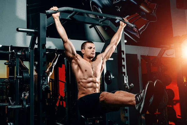 bodybuilder on the bar raises his legs up, exercises on the press in the gym. Great training of a professional bodybuilder.