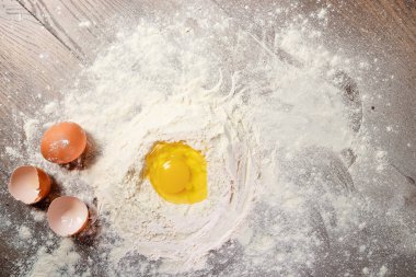 Üstten Görünüm bir yumurta, un, hamur ahşap bir masa arka planı yemek içine dövülmüş. Düz yatıyordu