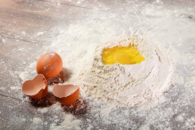 Üstten Görünüm bir yumurta, un, hamur ahşap bir masa arka planı yemek içine dövülmüş. Düz yatıyordu