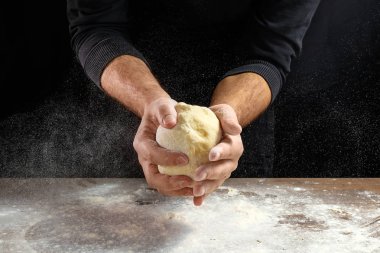Erkek elinde Şef yakın çekim, hamur yoğurmak, karanlık bir arka plan üzerinde hamur yemek.
