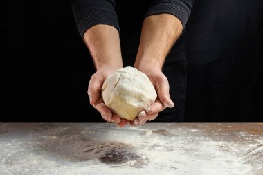 Erkek elinde Şef yakın çekim, hamur yoğurmak, karanlık bir arka plan üzerinde hamur yemek.
