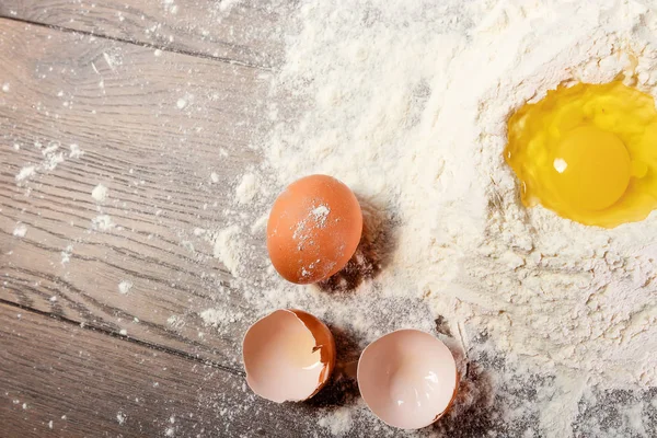 The top view of an egg, beaten into flour, cooking dough against the background of a wooden table. Flat lay, copy space.