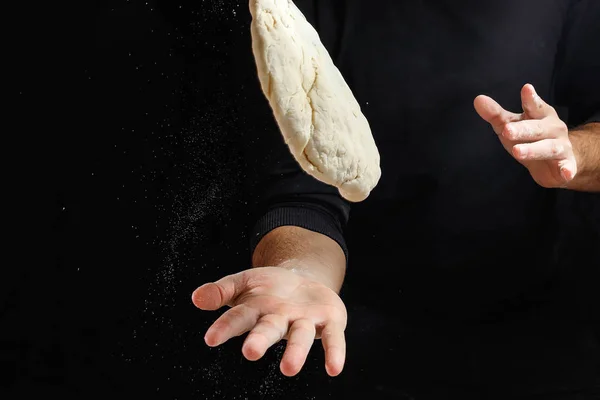 Male hand chef close-up. Preparation of Italian food pasta, pizza or bread focaccia. The recipe for cooking home-made dishes from the chef. Dark background.