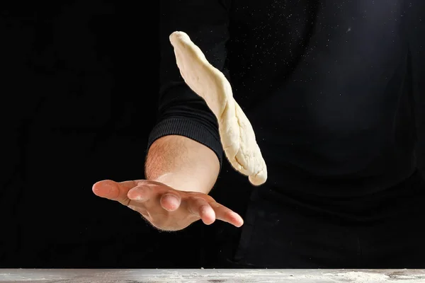 Male hand chef close-up. Preparation of Italian food pasta, pizza or bread focaccia. The recipe for cooking home-made dishes from the chef. Dark background.