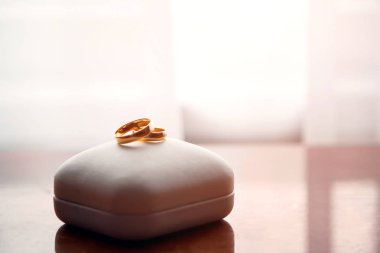 Wedding gold rings lie on a box clipart