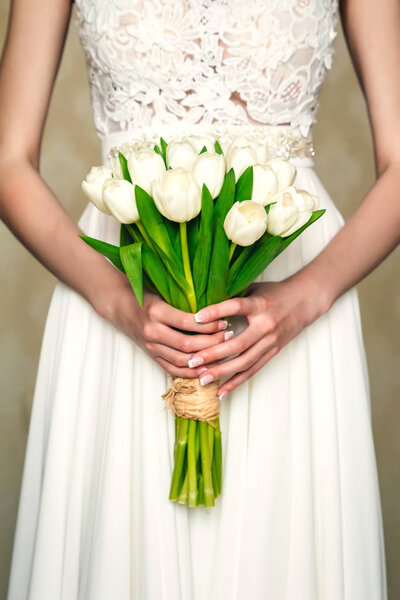 The bride holds a beautiful bouquet of flowers on a background of lake