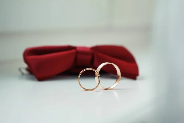 Gold wedding rings on a red butterfly on a windowsill