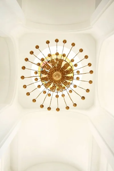 Gilded chandelier against the white ceiling