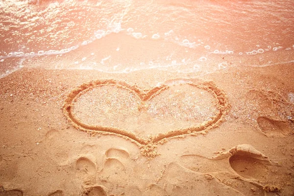 A loving couple draws a heart on the sand on the beach