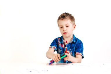 Beyaz arka plan izole kalem ile 6 yaşında bir çocuk mavi gömlekli boyar