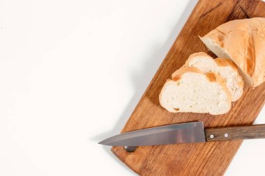 Beyaz bir arka plan üzerinde yukarıdan bir bıçak manzaralı bir mutfak tahtada beyaz ekmek yatıyor
