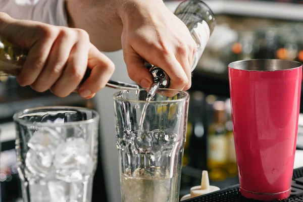 Männliche Hände des Barkeepers in Nahaufnahme, macht einen Cocktail an der Bar, Gläser mit Eis. — Stockfoto