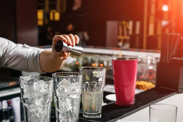 Männliche Hände des Barkeepers in Nahaufnahme, macht einen Cocktail an der Bar, Gläser mit Eis. — Stockfoto