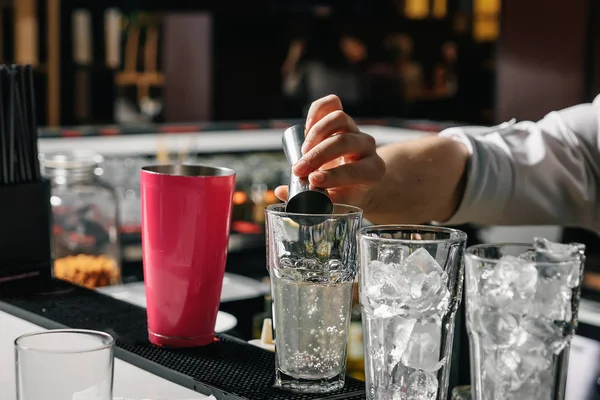 Männliche Hände des Barkeepers in Nahaufnahme, macht einen Cocktail an der Bar, Gläser mit Eis. — Stockfoto