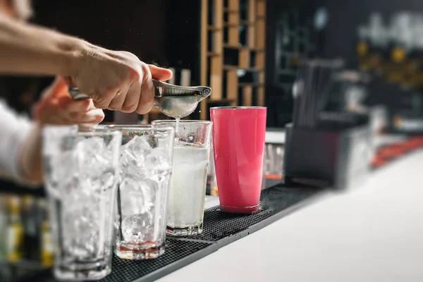 Männliche Hände des Barkeepers in Nahaufnahme, macht einen Cocktail an der Bar, Gläser mit Eis. — Stockfoto