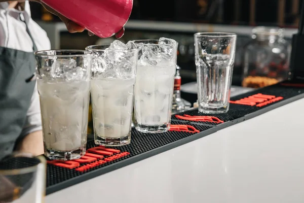 Männliche Hände des Barkeepers in Nahaufnahme, macht einen Cocktail an der Bar, Gläser mit Eis. — Stockfoto